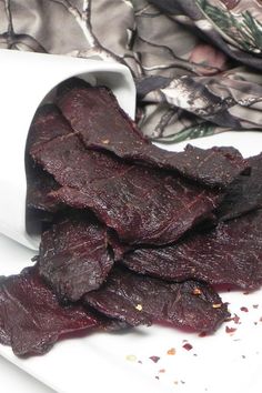 a pile of beef sitting on top of a white plate next to a roll of paper