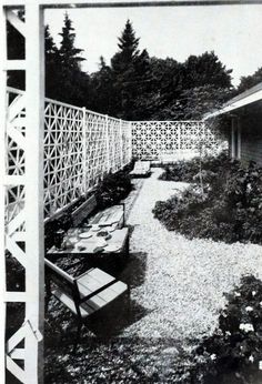 an old black and white photo of a bench in the middle of a garden area