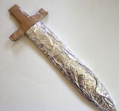 a wooden cross mounted on top of a metal object with silver foil wrapped around it