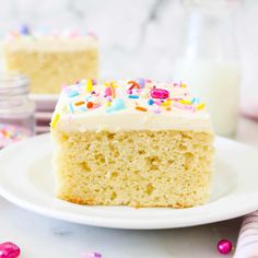 a slice of cake with white frosting and sprinkles on a plate