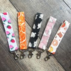 four lanyards are lined up on a wooden floor, one has an orange and the other is pink