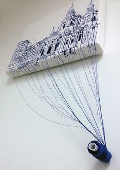 a drawing of a building on the wall next to a pair of scissors and thread