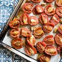 sliced tomatoes on a baking sheet ready to be cooked in the oven for roasting