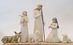 figurines of three people and two dogs on a wooden base with a white background