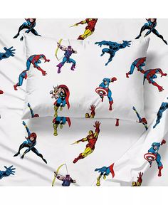 the bedding is made up with superheros and captain america symbols on white sheets