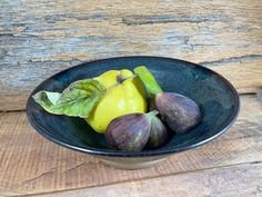 a bowl filled with figs on top of a wooden table