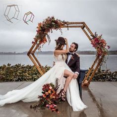 a bride and groom posing for a photo in front of an arch with flowers on it