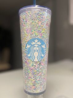 a starbucks cup with sprinkles and a blue straw in the bottom half