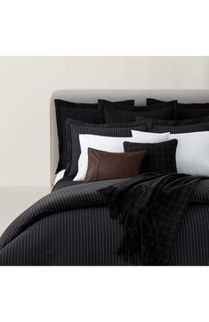 a bed with black and white comforters, pillows and blankets on top of it