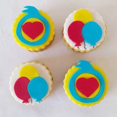 three decorated cookies sitting on top of a white table next to each other with blue, red and yellow icing