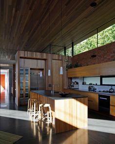 a kitchen with wooden cabinets and stools next to an open floor plan that has wood paneling on the walls