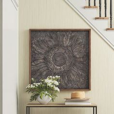 a vase with flowers sitting on top of a table next to a stair case and railing