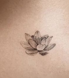 a black and white photo of a lotus flower on the back of a woman's stomach