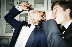 two men in suits are drinking from wine glasses