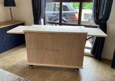 a kitchen island made out of plywood with wheels on the bottom and an open window behind it