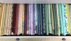 a shelf filled with lots of different colored fabrics