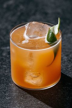 an orange drink in a glass with a lime garnish on the rim and ice