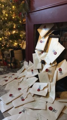 a pile of envelopes sitting next to a christmas tree in front of a fireplace