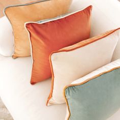 three different colored pillows sitting on top of a white couch next to eachother