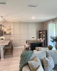 a living room filled with furniture next to a kitchen and dining room table in front of a large window