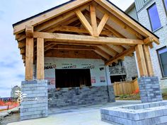 a building under construction with wooden beams on the roof and brick pillars in front of it