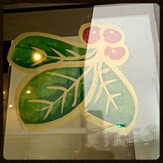 a close up of a sticker on the side of a glass window with leaves and berries