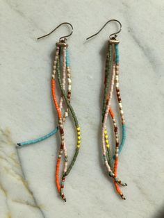 two pairs of multicolored beaded earrings sitting on top of a marble counter