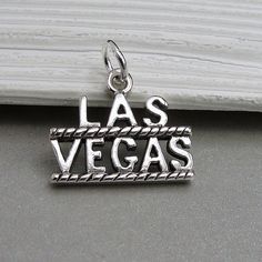 "This Las Vegas Charm comes with a silver jump-ring as pictured. Please note that photo is not to scale and may appear larger to show detail. Refer to exact measurements below. Additional attachments (lobster clasp, large-hole bead, necklace chains) are available from the charm-attachments drop-down menu.  For a visual example of the different attachments and what each one is best suited for, scroll through the photos until you see the example photo or visit https://etsy.me/2BY7DAW for detailed information.    { DETAILS } ★ Material: Sterling Silver ★ Finish Color: Silver  ★ Measurements: 1/2\" x 3/4\" ★ Dimensions: One-sided ★ Made in the USA { SIMILAR ITEMS }  More casino and gambling themed items available from my shop: https://www.etsy.com/shop/treasuredcharms/search?search_query=casin Engraved Silver Charms, Personalized Silver Charm Bracelet With Pendant, Silver Nickel-free Bracelet Souvenir, Nickel-free Silver Bracelets As Souvenir, Silver Symbolic Jewelry Souvenir, Adjustable Engraved Silver Charms, Casino Theme Necklace, Personalized Sterling Silver Charms For Collectors, Nickel-free Silver Charms Souvenir