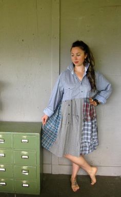 a woman leaning against a wall next to a green filing cabinet with drawers on it