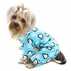 a small dog wearing a blue penguin pajama set with snowflakes on it