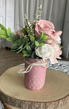 a pink vase filled with flowers on top of a wooden table