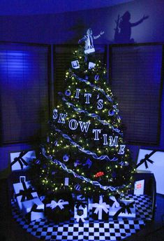 a decorated christmas tree in the corner of a room with black and white checkered flooring