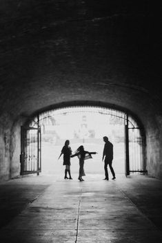 three people standing in front of an open door with one person holding the other's hand