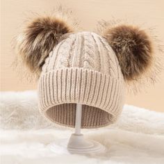 a white hat with two brown pom - poms sitting on top of it