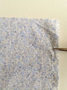 a pair of scissors cutting through the fabric on a piece of cloth with blue and white flowers