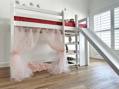 there is a bunk bed with pink netting on it and a slide in the corner