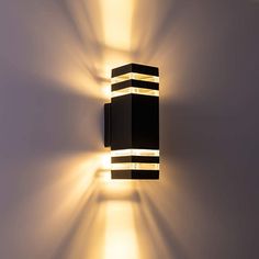 a black and white striped light fixture on a wall in a room with no one around it