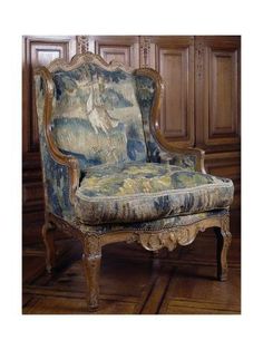 an ornate chair with blue and yellow upholstered fabric on the armrests