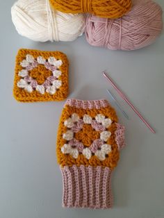 three crocheted items are sitting next to each other on a table with knitting needles