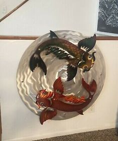 a metal plate with two fish in the middle and one fish on it's side