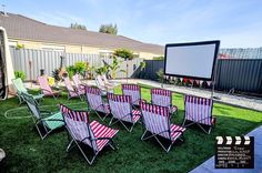 a group of lawn chairs sitting on top of a lush green field next to a movie screen