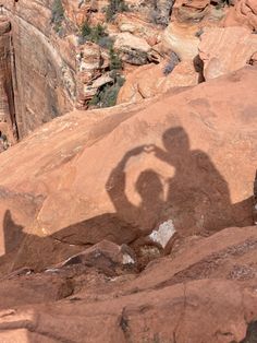 the shadow of two people standing on top of rocks