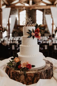 a white wedding cake sitting on top of a wooden slice