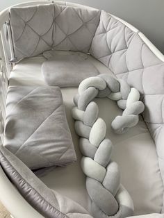 a baby crib with pillows and blankets on it's sides, in the shape of a knot