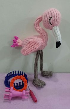 a crocheted flamingo is standing next to a hair brush and comb holder