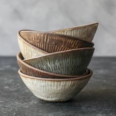 four bowls stacked on top of each other in front of a gray wall and floor