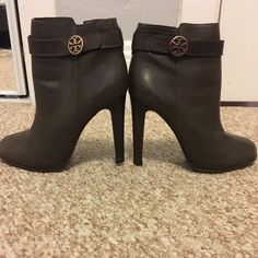 Tory Burch Bootie With Logo Medallion On The Side And Genuine Leather. The Heel Height Is Approximately 3 1/4 Inches With 3/4 Inch Platform. The Boot Shaft Height Is Approximately Four Inches. The Color Is Similar To An Olive-Grey Color. Brown Round Toe Boots With Heel Strap, Brown Boots With Heel Strap And Round Toe, Tory Burch Shoes, Grey Color, Bristol, Bootie, Bootie Boots, Tory Burch, Gray Color