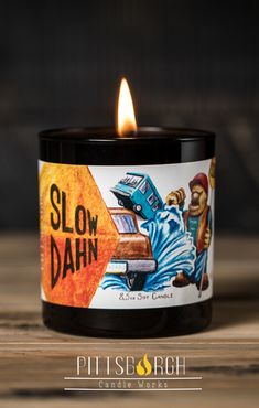 a candle that is sitting on top of a wooden table with the words slow dahn written