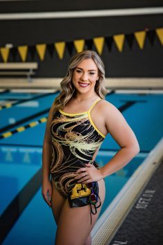 a woman in a swimsuit standing next to a swimming pool with her hands on her hips