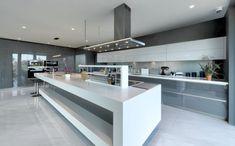 a modern kitchen with white counter tops and stainless steel appliances, along with an island in the middle